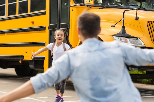 Père rencontre petite fille sortant du bus scolaire