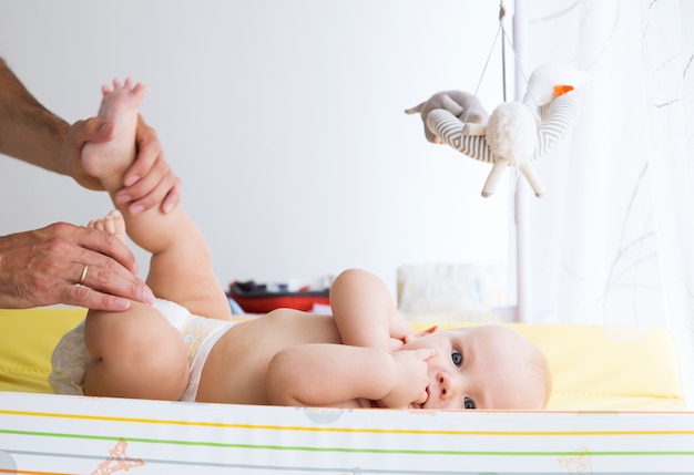 Père s'occupe doucement de bébé sur la table à langer à la maison