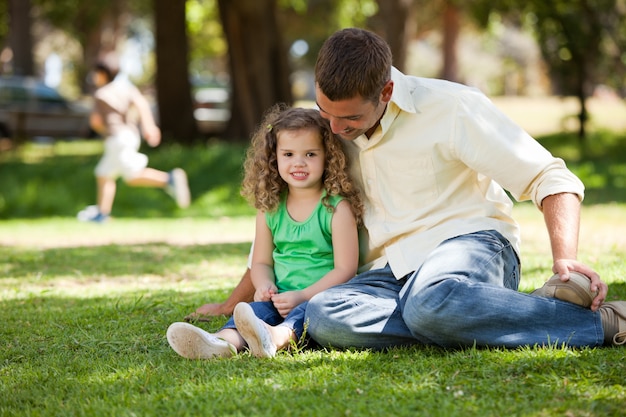 Père avec sa fille assise sur le jardin