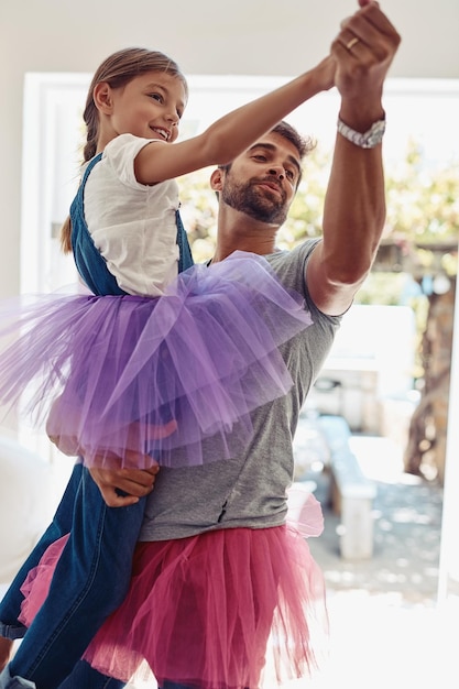 Père avec sa fille dansant en tutu ludique et amusant à la maison avec des liens avec amour et soin Un homme de famille et une fille dansent dans le salon sans soucis et passent du temps ensemble avec relation et joie