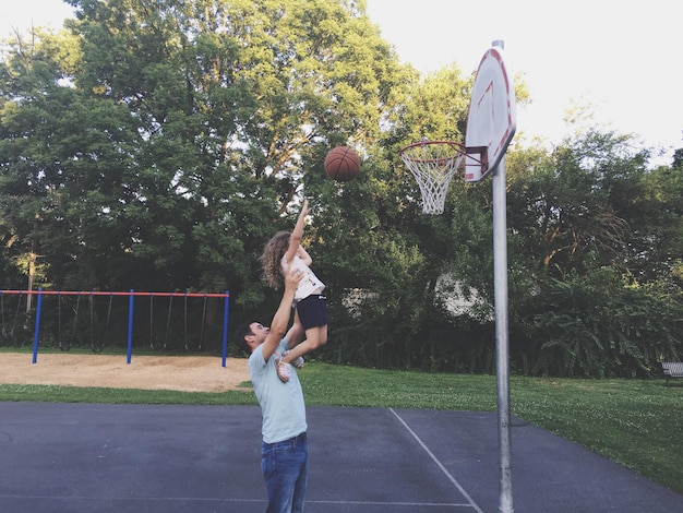 Un père et sa fille jouent au basket.