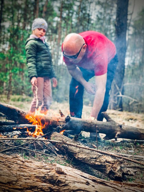 Photo un père et sa fille près d'un feu de joie dans la forêt