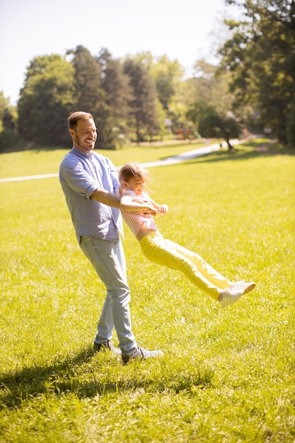 Père avec sa fille s'amusant sur l'herbe au parc