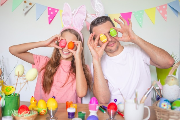 Père et sa petite fille peignant des œufs. Héhé, préparation pour Pâques.