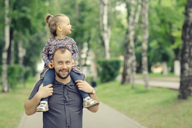 Un père se promène avec sa fille dans le parc.