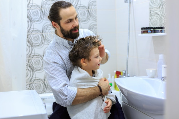 Père séchant son fils avec une serviette après le bain