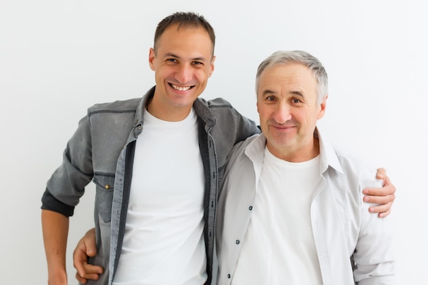 Photo père senior avec fils adulte sur un mur blanc