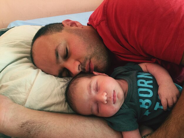 Photo un père et son fils dorment sur un lit à la maison.