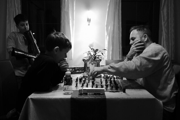 Photo un père et son fils jouent aux échecs à la maison.