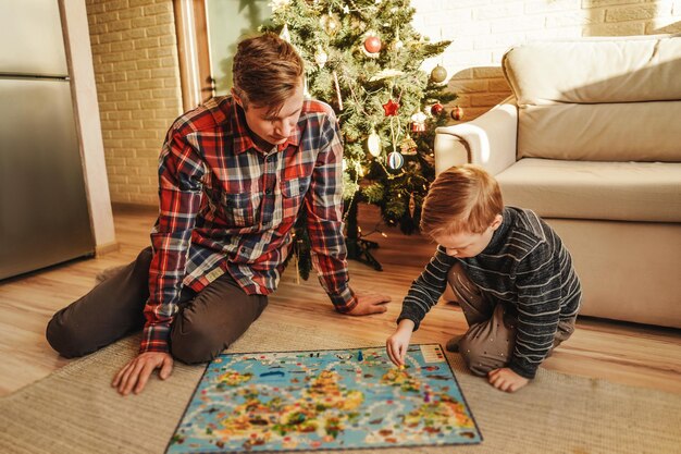 Photo un père et son fils jouent à un jeu de société à la maison.