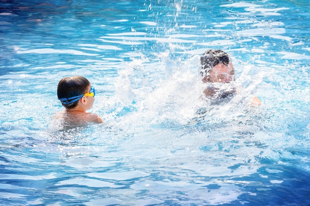 Un père et son fils jouent à la piscine en vacances.