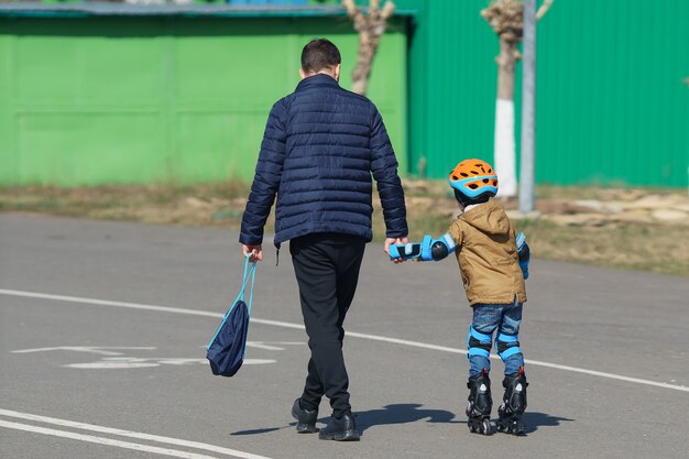 Père avec son fils en promenade. Roller.