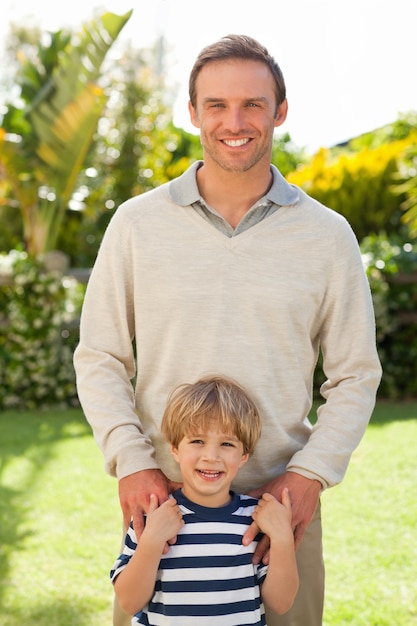 Père et son fils en regardant la caméra dans le jardin