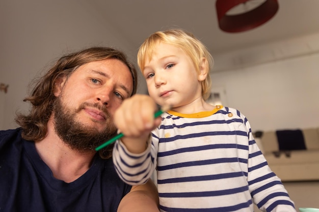 Père avec son mignon petit fils tenant un crayon de couleur