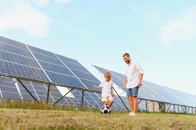 Un père et son petit fils jouent au football près des panneaux solaires.