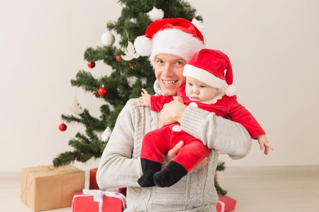 Père avec son petit garçon portant des chapeaux de Père Noël pour célébrer Noël