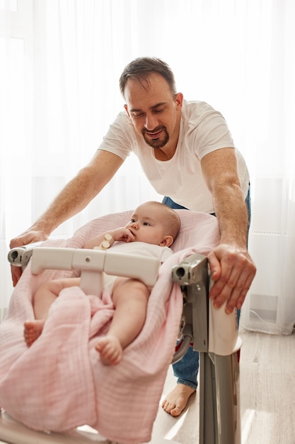 Un père souriant et heureux tient un siège enfant dans lequel son bébé bien-aimé est assis une parentalité heureuse et un enfant