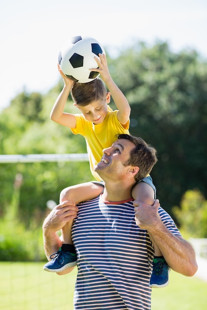 Père souriant portant son fils sur l'épaule