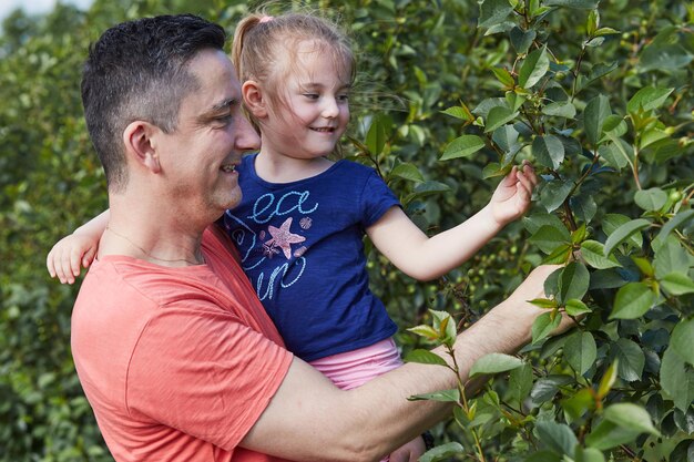 Photo un père souriant avec sa fille touchant des plantes dans un champ agricole