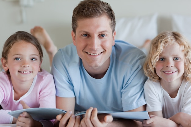 Père souriant avec ses enfants et un magazine