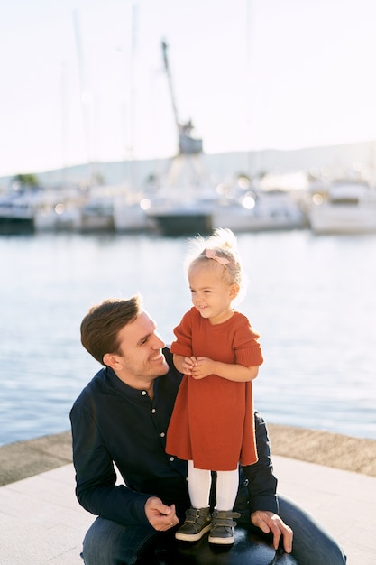 Père sourit à son daghter sur un quai de bateau au bord de la mer.