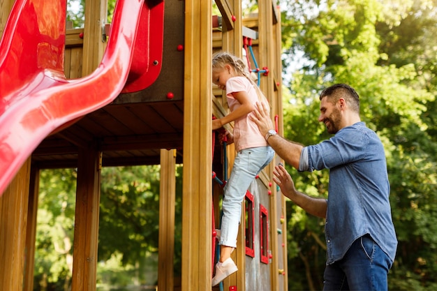 Père soutenant et tenant son enfant fille dans les escaliers à l'aire de jeux pour enfants père et fille