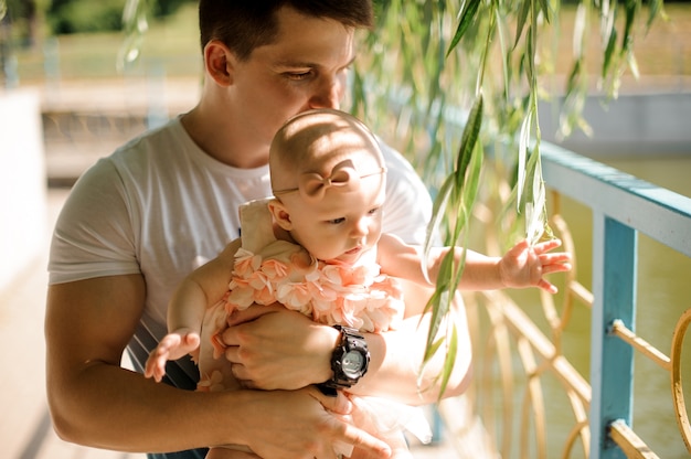 Père tenant sa petite fille sur les mains parmi le saule