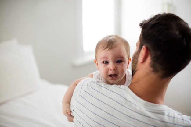 Père tenant sa petite fille qui pleure à la maison