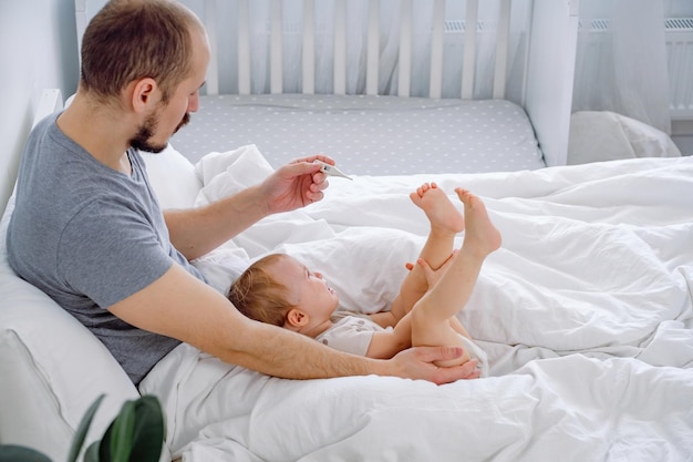 Père tenant son bébé qui pleure et mesurant la température Maladie thérapie médecine grippe