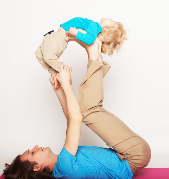 Père tenant son petit fils sur ses pieds, yoga, famille heureuse