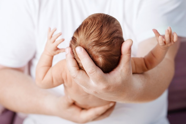 Père tenant la tête de son nouveau-né dans les mains. Aimer la main du père tenant mignon bébé nouveau-né endormi. Belle image conceptuelle de la parentalité