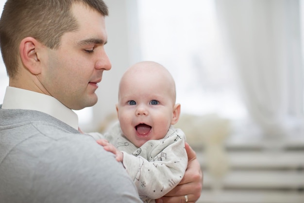 Le père tient le bébéBébé joyeux dans les bras du parent