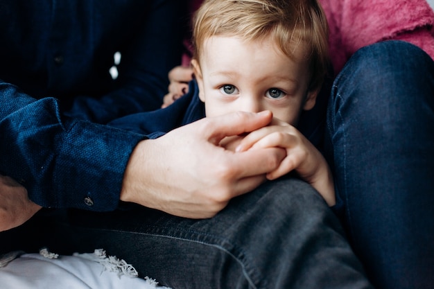 Père tient le bras du petit fils assis sur le lit