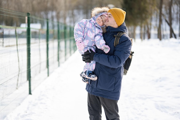 Le père tient l'enfant sur les mains lors d'une journée d'hiver glaciale et ensoleillée dans le parc