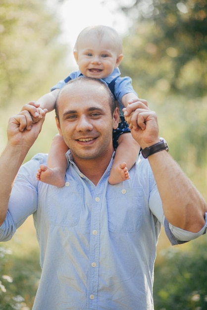 Le père tient le petit fils dans des ses bras en parc d'été