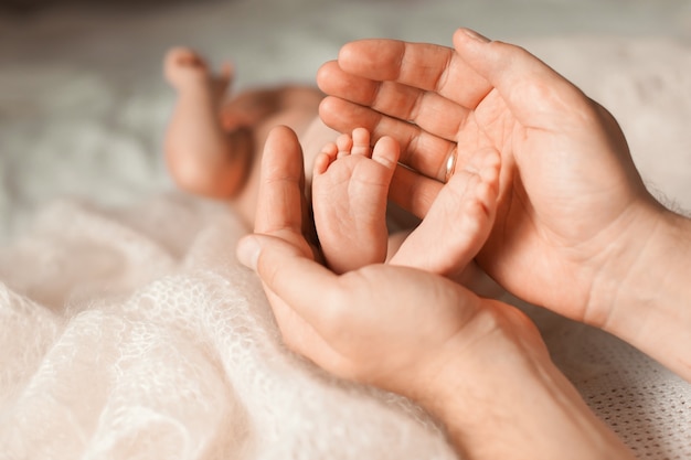 Le père tient les pieds du nouveau-né dans ses paumes