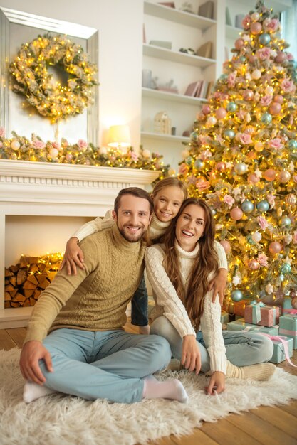 Période de Noël. Jeune famille heureuse assis sur le sol près de l'arbre de Noël Ð¡ et se sentir à l'aise