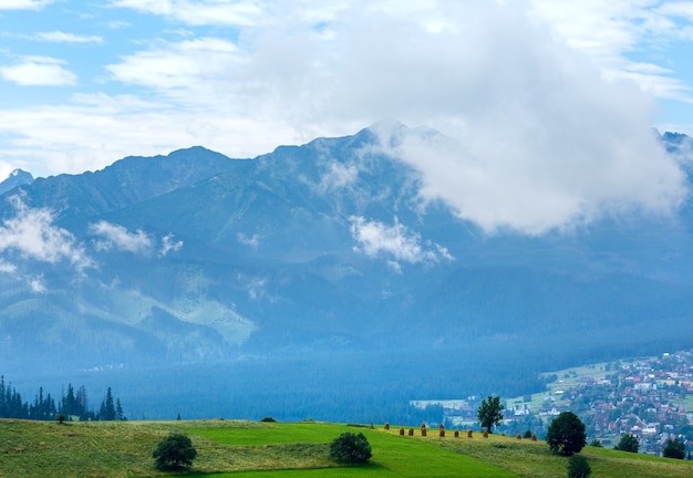 La périphérie du village de montagne brumeux d'été avec la chaîne des Tatras (Gliczarow Gorny, Pologne)