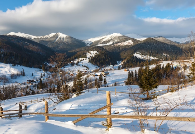 Périphérie du village de montagne du matin d'hiver et crête des alpes