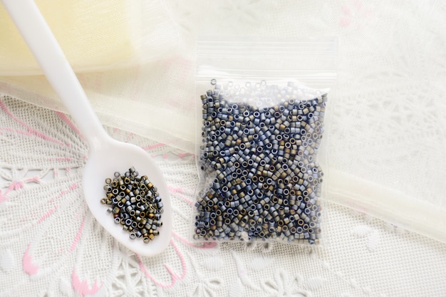 Perles colorées sur une surface en tissu blanc, diverses formes et couleurs pour la fabrication de bijoux