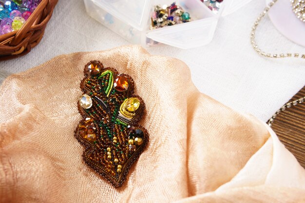 Perles faites main de chêne d'automne de feuille de broche sur la table sur un fond jaune