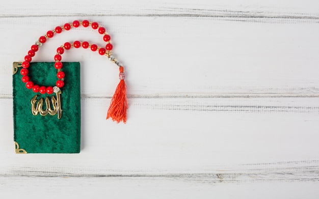 Photo perles de prière rouge sur la couverture verte islamique livre sacré kuran sur le bureau blanc