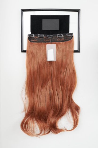Perruque d'apparence naturelle de couleur brune dans les cheveux d'un salon de beauté sur une étagère dans un magasin de perruques
