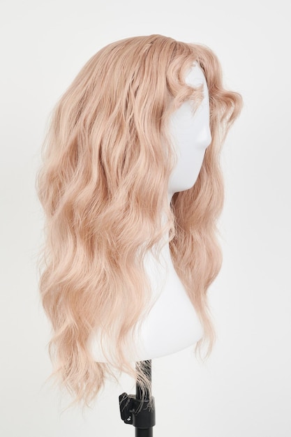 Perruque blonde d'apparence naturelle sur la tête blanche du mannequin Cheveux longs sur le support de perruque en plastique isolé sur fond blanc