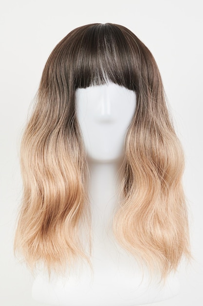 Perruque blonde d'aspect naturel sur tête de mannequin blanche cheveux mi-longs coupés sur le porte-perruque en plastique isolé sur fond blanc vue de face