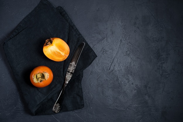 Persimmon mûr, couteau sur fond noir