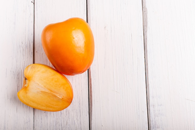 Persimmon orange mûr sur fond en bois blanc