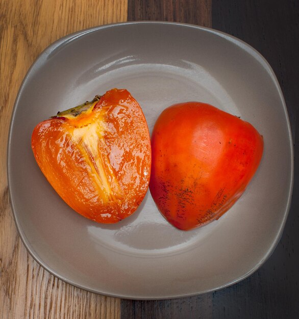 Photo des persimmons frais sur une assiette sur une table en bois