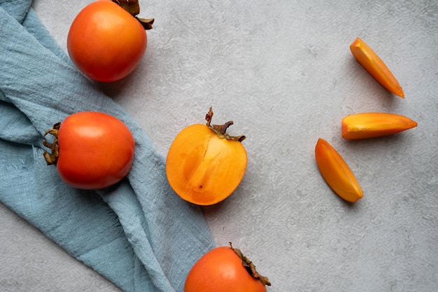 Des persimmons sur une table grise avec des coins de tissu de sharon