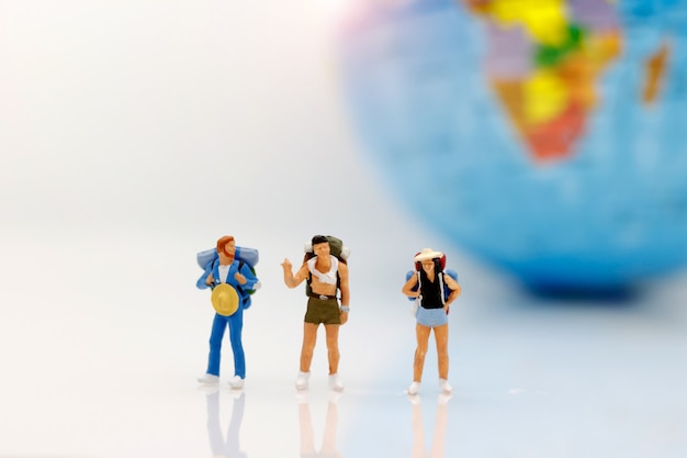 Personnages miniatures, routards avec globe marchant à destination.